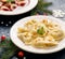 Christmas dumplings stuffed with mushroom and cabbage on a white plate on a dark background.