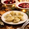 Christmas dumplings stuffed with mushroom and cabbage on a white plate on a wooden table.