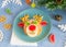 Christmas edible deer of buns and marmalade on a blue plate on the holiday table next to candy, snowflakes and branches
