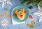 Christmas edible deer of buns and marmalade on a blue plate on the holiday table next to candy, snowflakes and branches of the