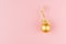 Christmas elegant background - golden sparkling glossy ball with ribbon on soft light pastel pink background, copy space, top view