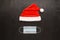Christmas era covid concept. Medical protective mask and Santa Claus hat on a dark brown background.