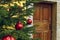 Christmas eve rustic house porch outdoor view decorated tree by festive red balls and poor wooden entrance door