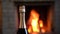 Christmas evening. Bottle of Champagne wine on the background of burning cozy fireplace, in country house.