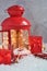 Christmas fairy composition of red lantern with Christmas tree and lights inside, decorative skis, sledges with decorations, gifts