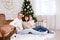 Christmas and family concept - happy young parents and cute little baby girl daughter near decorated christmas tree