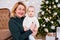 Christmas and family concept - portrait of grandmother and little baby girl near decorated christmas tree