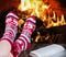 Christmas female legs in socks on the background of a burning fi