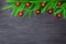 Christmas festive border, New Year decorative frame, shiny red balls decorations on green fir branches on black wooden background