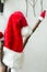 Christmas festive home interior decoration. Big and small Santa Claus hats hanging on tree branches. White wall background