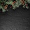 Christmas Fir branches with pine cones on dark black background. Xmas and Happy New Year card, bokeh, sparking, glowing.