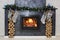 Christmas fireplace with a fire burning in it, new year garland and firewood for kindling. A silver-gray fireplace