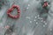 Christmas flat lay in grey, green, white and red. Xmas background with heart shape wreath made of red berries, decorated fir twigs