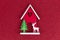 Christmas flatlay layout. wooden toy house, a deer and a Christmas tree on a red glitter shiny background. Christmas card with
