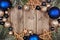 Christmas frame with dark blue and gold ornaments and tree branches, above view on a wood background