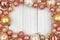 Christmas frame of rose gold and golden ornaments on white wood