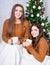 Christmas and friendship concept - girls talking and drinking co