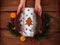 Christmas fruitcake in child hands powdered sugar tangerine cranberry fir tree festive decoration wooden table flat lay
