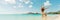 Christmas fun travel vacation bikini girl jumping of joy on Caribbean beach santa hat woman happy panoramic banner