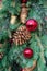 A Christmas garland featuring pine cones, red shiny balls and pine needles.