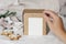 Christmas gift box label mockup scene. Closeup of womans hand holding gift box. Velvet ribbons, gingerbread cookies and