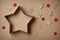 Christmas gift box in the shape of a star, surrounded by decorations, on cardboard background