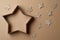 Christmas gift box in the shape of a star, surrounded by decorations, on cardboard background