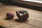 A Christmas gift box tied with a white and red ribbon, on a wooden rustic table, next to a packing rope. Packaging of Christmas