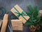 Christmas gift boxes on holiday background with Fir branches, pine cones, craft paper rolls, ribbons, twine and scissors.