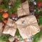 Christmas gifts in craft paper package tied a rope on wooden background in a frame christmas tree branches decorations.