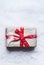 Christmas gifts in craft paper with red ribbon on snow background, top view with copy space for your greeting design