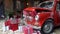 Christmas gifts packed with red, white, craft paper and tapes under decorated retro red car with trunk full of New Year