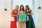Christmas gifts, three young ladies with present bags posing in elegant dress