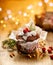 Christmas gingerbread muffin covered with icing decorated with cranberry and rosemary on a wooden table, twinkle lights, copyspace