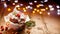 Christmas gingerbread muffin covered with icing decorated with cranberry and rosemary on a wooden table, twinkle lights, copyspace