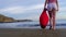 Christmas Girl Santa Claus walking at ocean sandy beach with large red bag full of presents - New Year vacation and