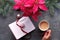 Christmas goals creative flat lay. Hand holding coffee, notebook with natural Xmas decorations, ribbon bookmark and pink trinket.