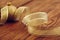 Christmas golden ball amid the yellow ribbon on Wooden background