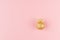 Christmas golden decoration as simple festive bright background - gold glittering ball with ribbon on pastel pink color, top view.