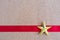 Christmas golden star and red ribbon on cork board.