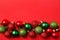 Christmas greating card composition. Christmas red and green balls decorations on red background. Flat lay, top view, copy space