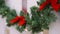 Christmas green garland with lights and red bows on white fence.