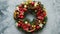 Christmas green, red and golden wreath with decorations isolated on stone background