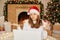 Christmas greetings online. Puzzled girl using her laptop for communication. having video calls to somebody, drinking hot tea,