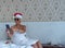 Christmas greetings online. A woman wearing a white towel, sunglasses and a red Santa hat uses her phone to make video calls to