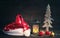 Christmas hat of Santa, Christmas lamp and glass spheres with a wooden decorative New Year tree on a wooden background