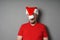 Christmas hater hiding face behind santa hat