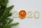 Christmas holiday background. Figures 2020 on a white wooden background, dried orange slices, spruce branches.