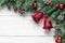 Christmas holiday composition with fir tree, christmas bells, berries and pine cones on white wooden background