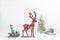 Christmas holiday composition. Red deer, doll girl in knitted clothes on the sled, Christmas tree and house. White background